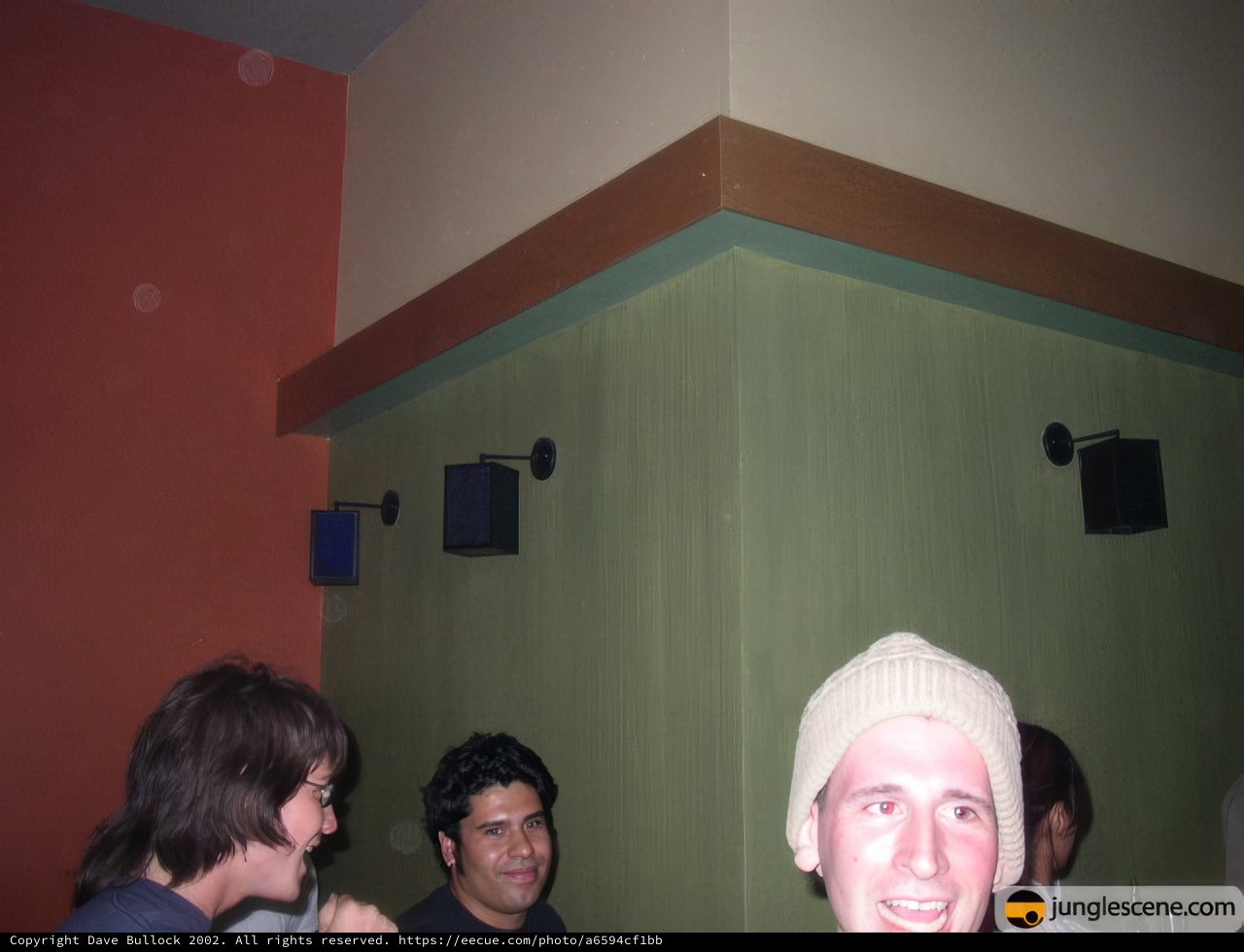 Group Gathering in Living Room with Hat-Wearing Man