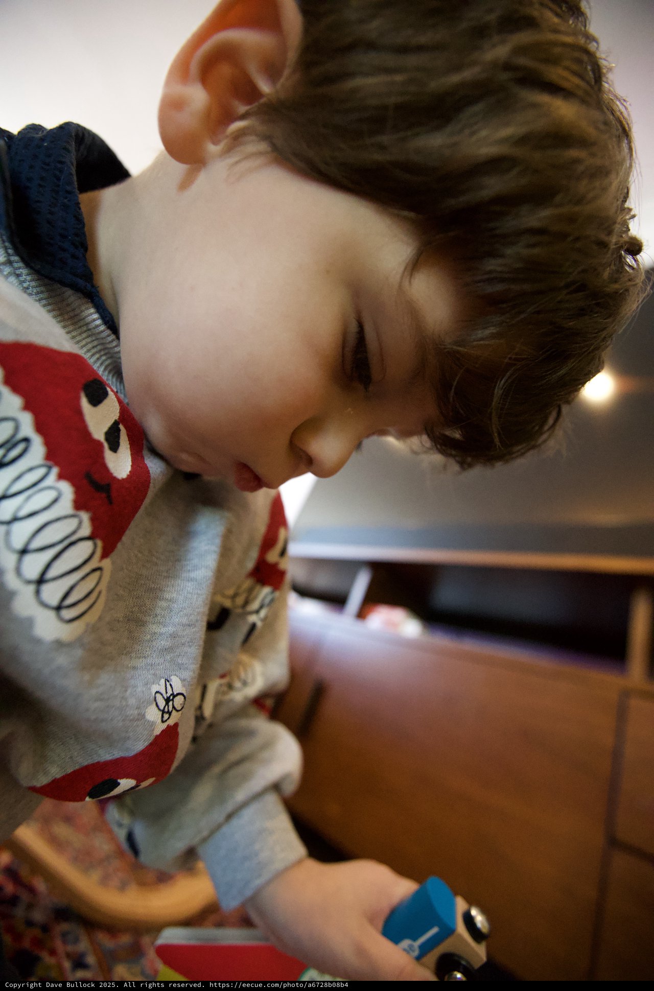 Young Child Focused on Play with Wooden Train Set
