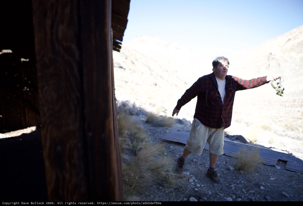 Explorer Holds Headlamp at Desert Ghost Town Ruins
