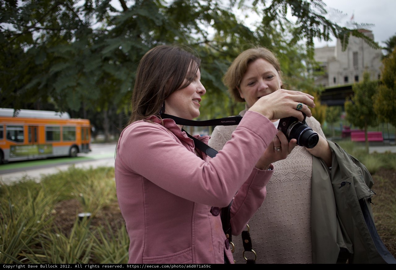 Two Women Sharing Photos on Olympus Camera Outdoors