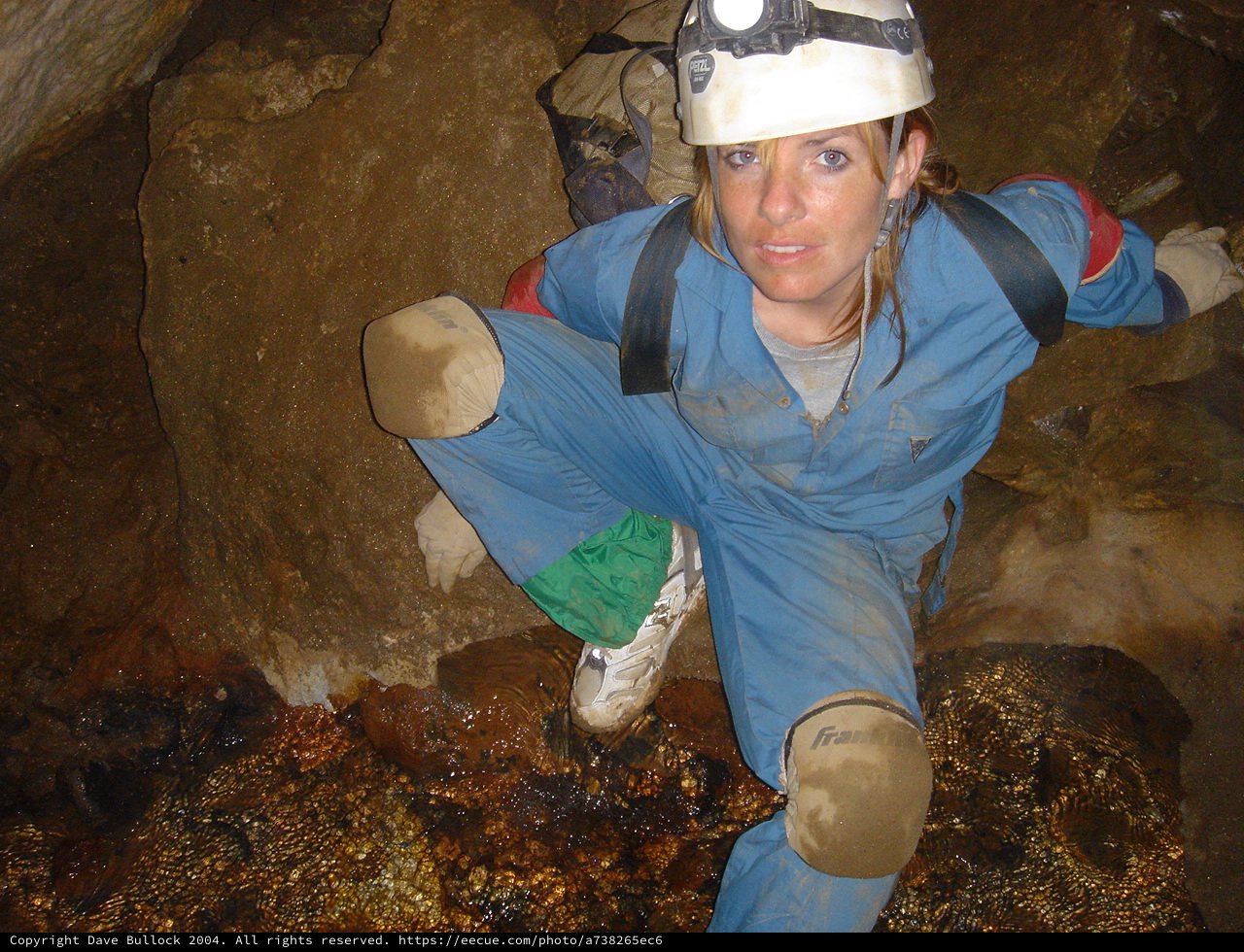 Female Caver Navigating Tight Underground Passage