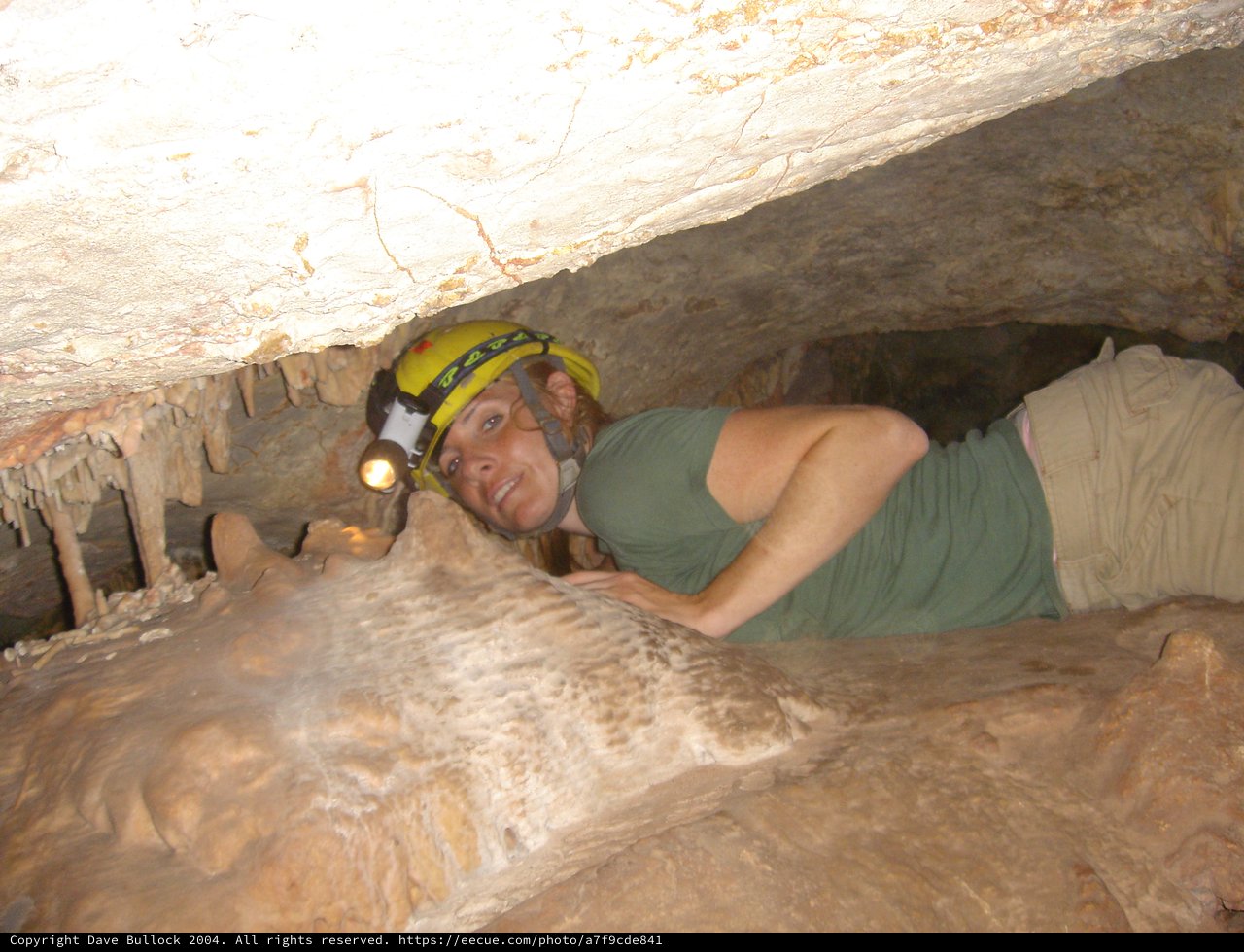 Caver Crawling Through Tight Underground Passage
