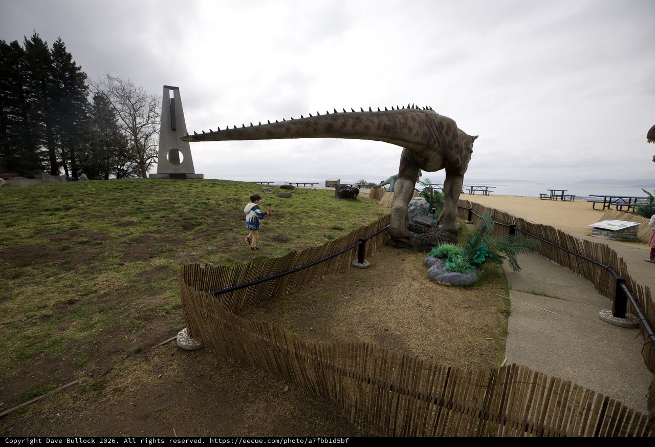 Child Encounters Life-Size Dinosaur Statue at Coastal Park