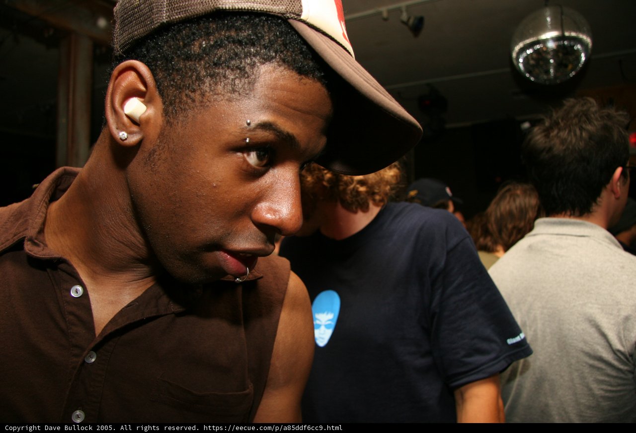 Brown Shirted Man with Two Hats