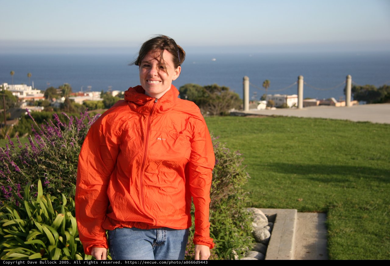 Smiling Woman in Orange Jacket by the Sea