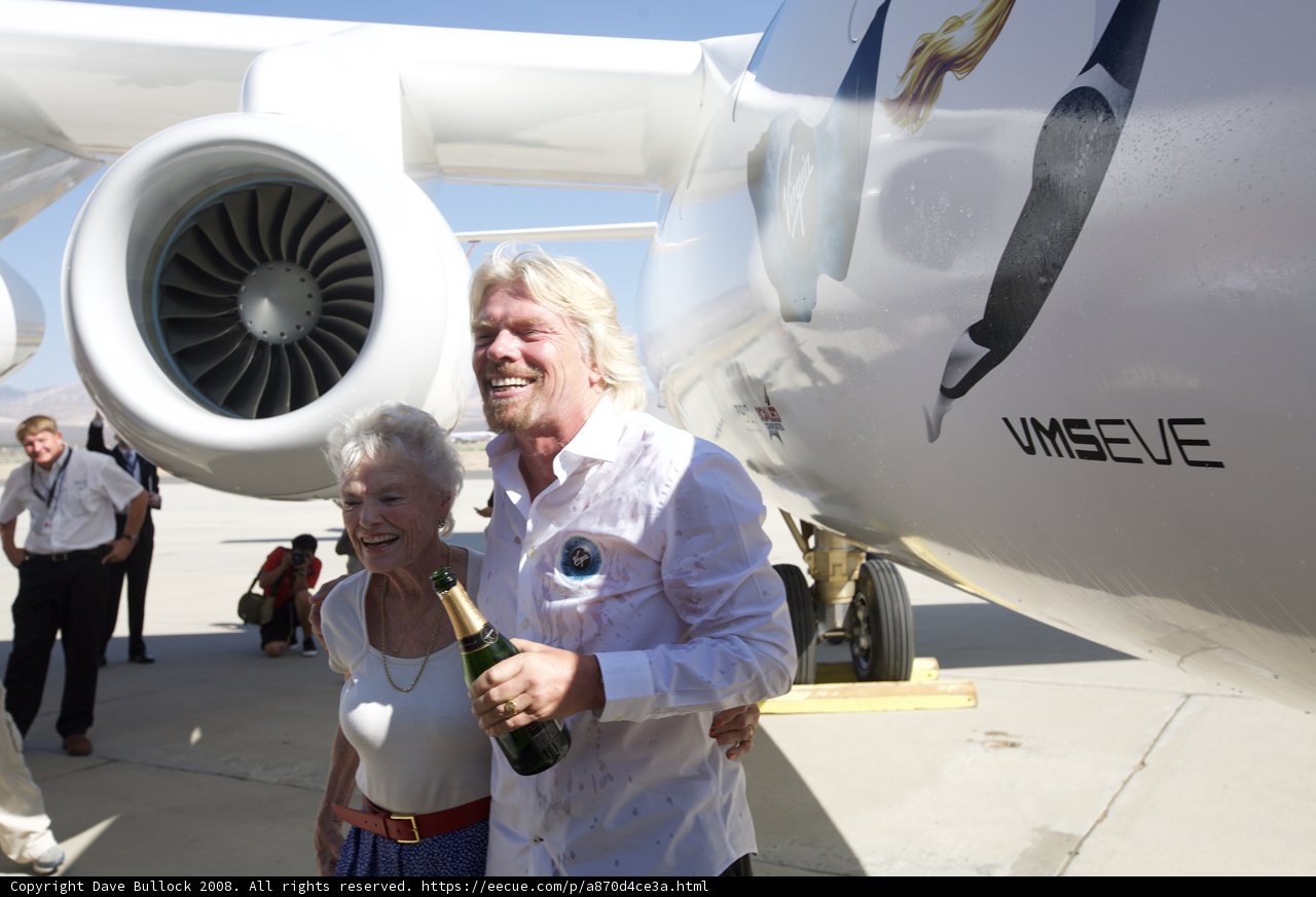 Richard Branson and a Companion Stand Tall Next to an Airplane