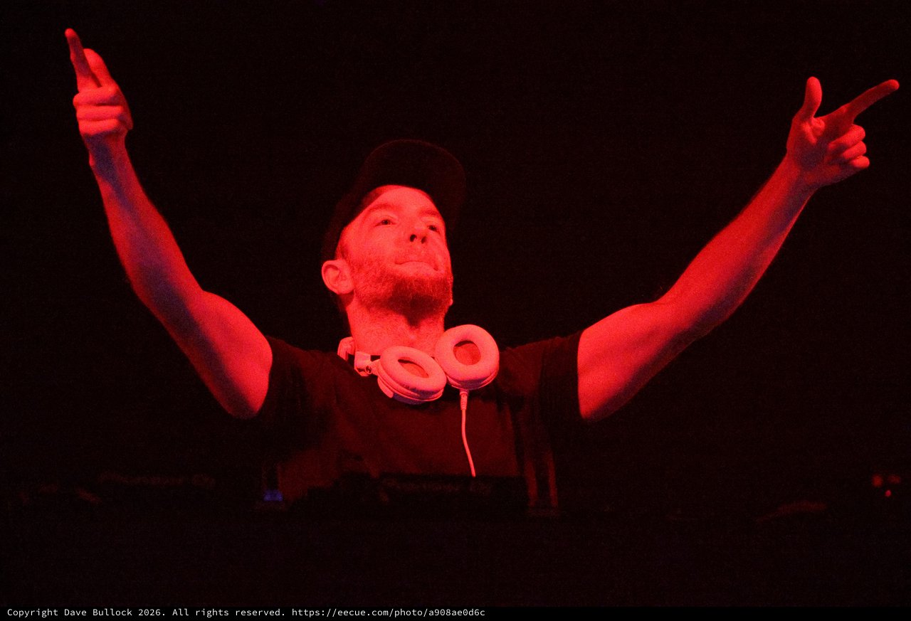 DJ Raises Arms Under Red Stage Lights at Wobbleland