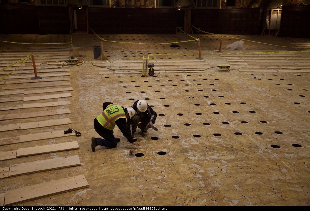 Two Workers Laying Plywood Flooring in Empty Room