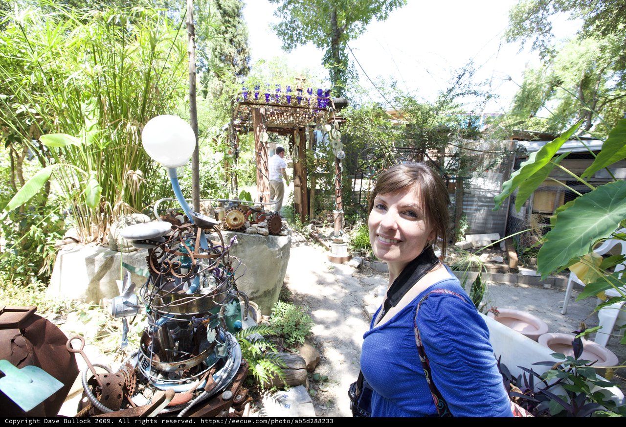 Woman Smiling Amid Eclectic Junk Art Garden