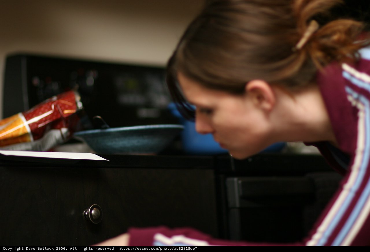 Young Woman Focused Over Kitchen Counter at Dusk