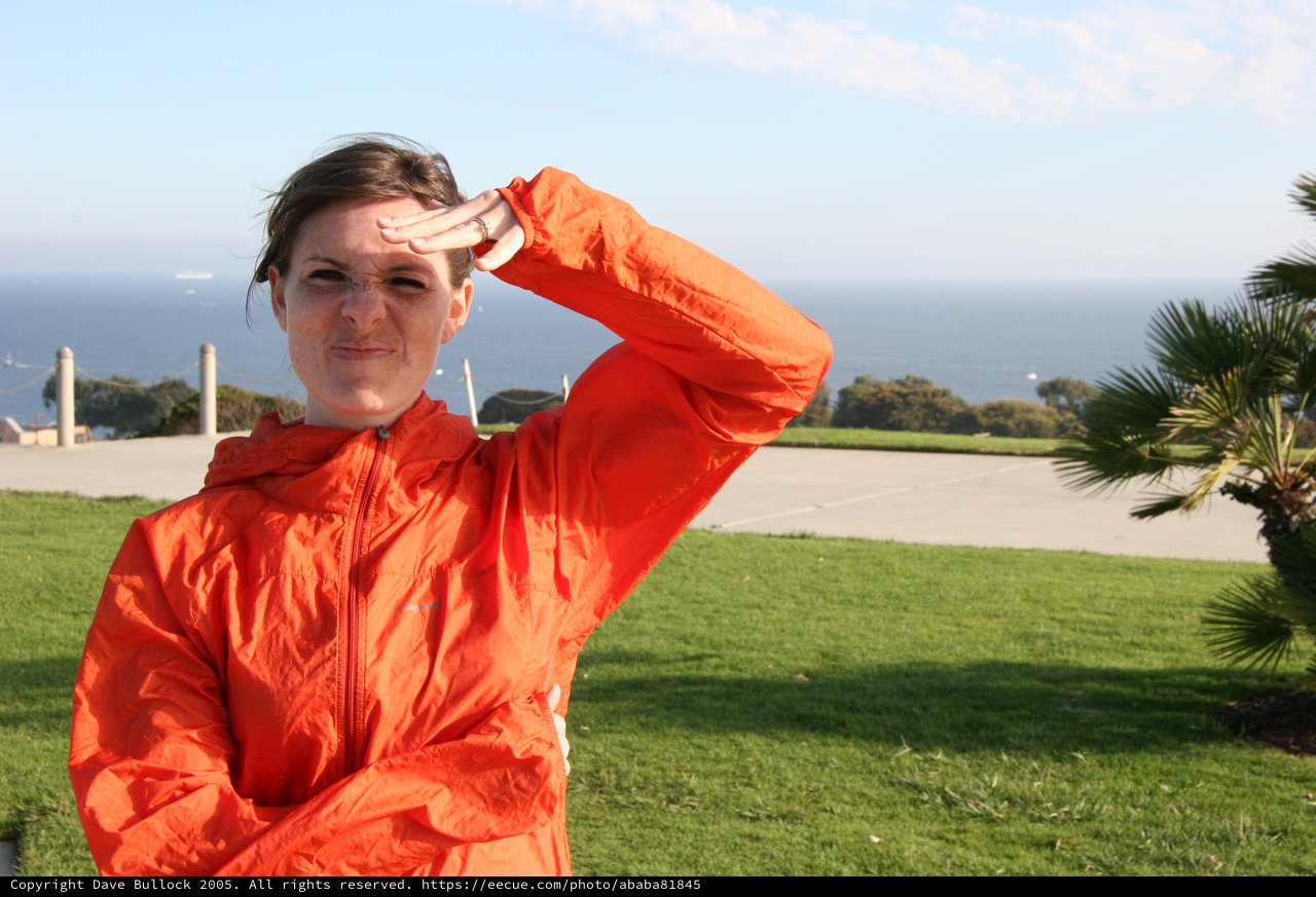 Woman in Orange Jacket Shielding Eyes Oceanside