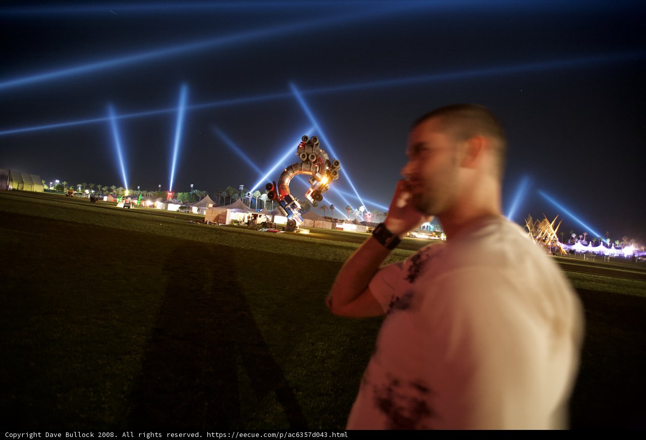 Man on Cell Phone in Front of Statue at Coachella