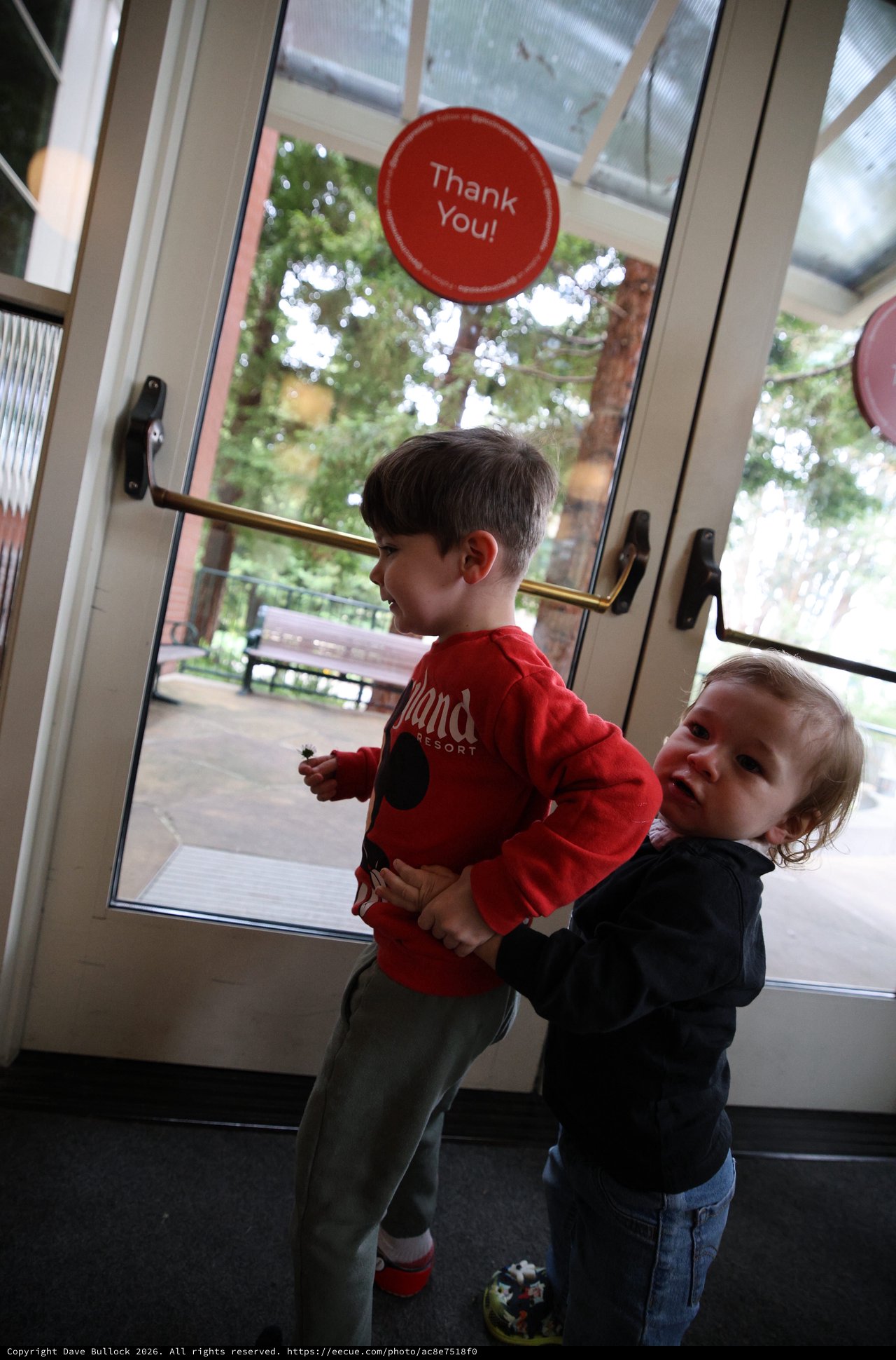 Two Young Children Playing Together at Glass Door Exit