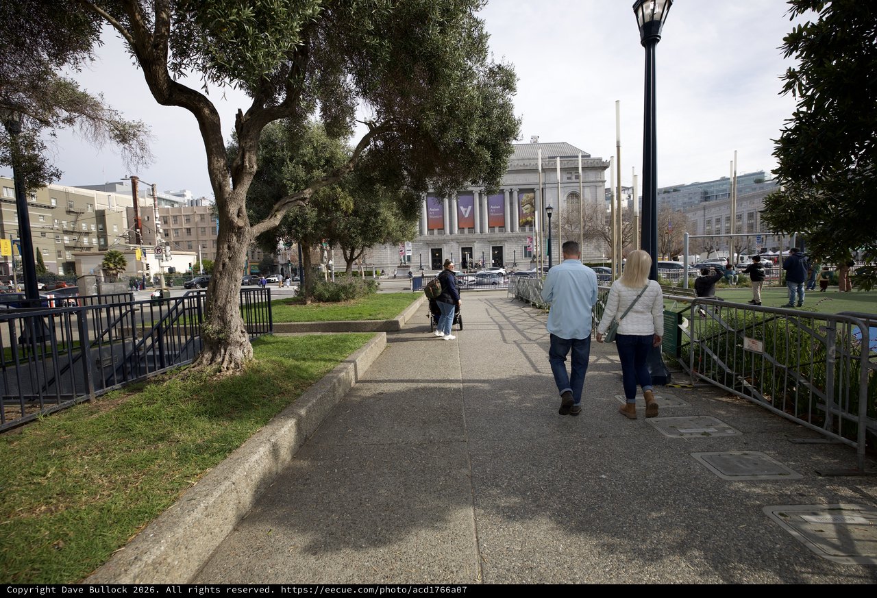Couple Walking Through Urban Park Toward Museum