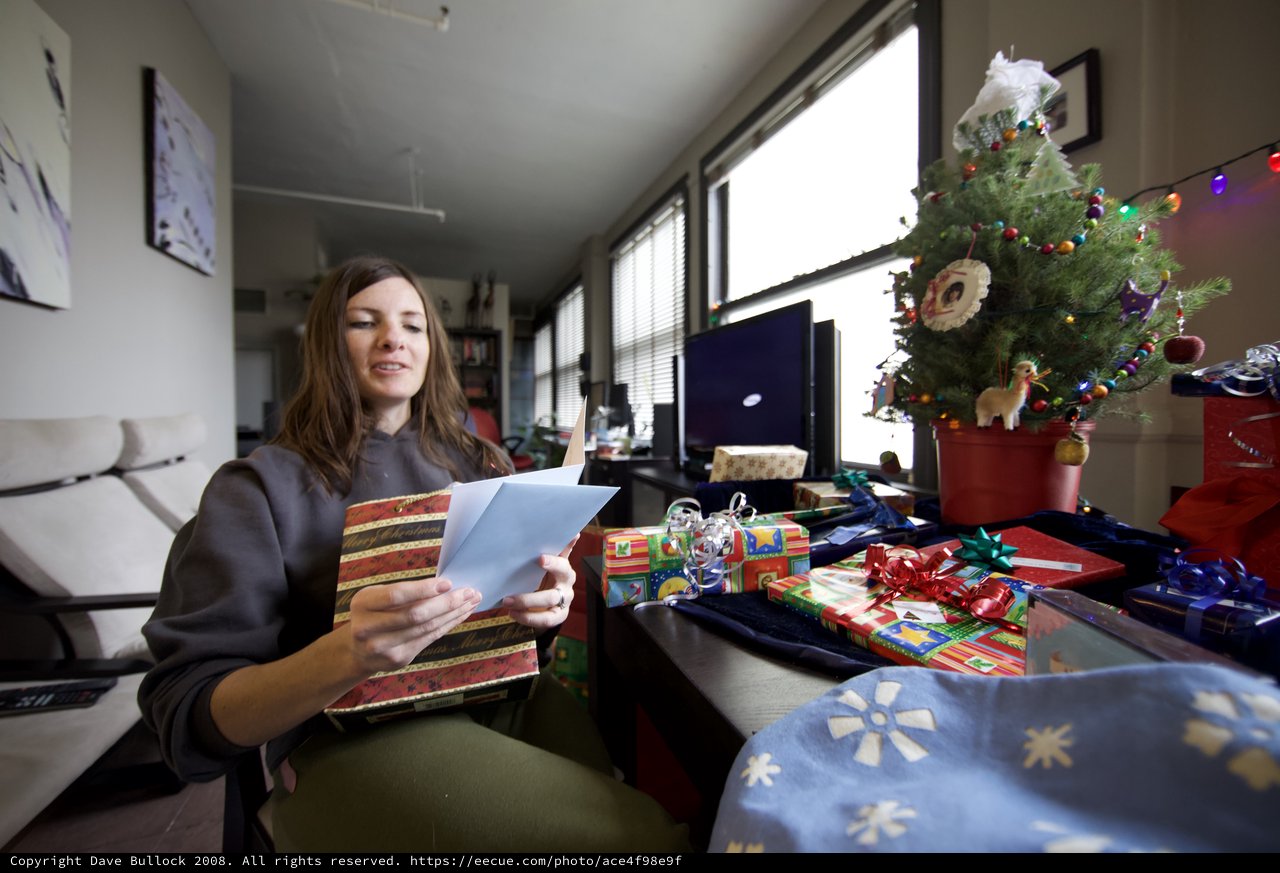 Woman Reading Christmas Card Among Holiday Gifts