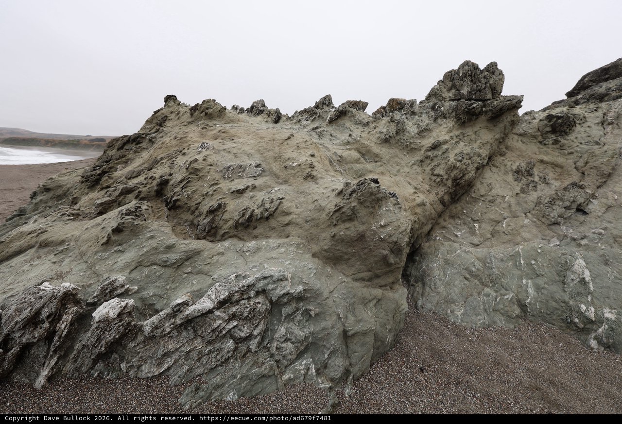 Jagged Coastal Rock Formation on Foggy Beach