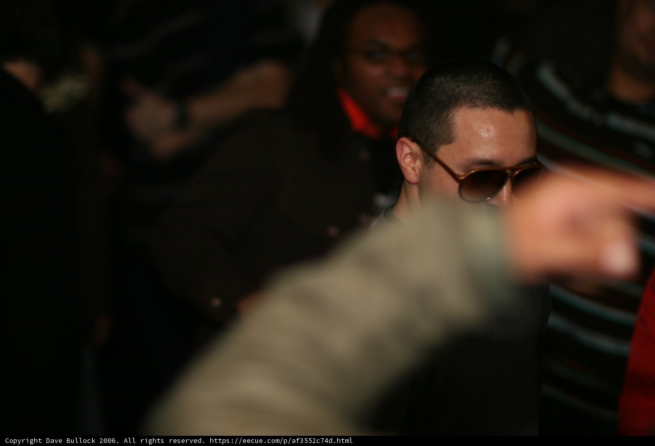 Man in Sunglasses Stands Out in Urban Nightlife Crowd