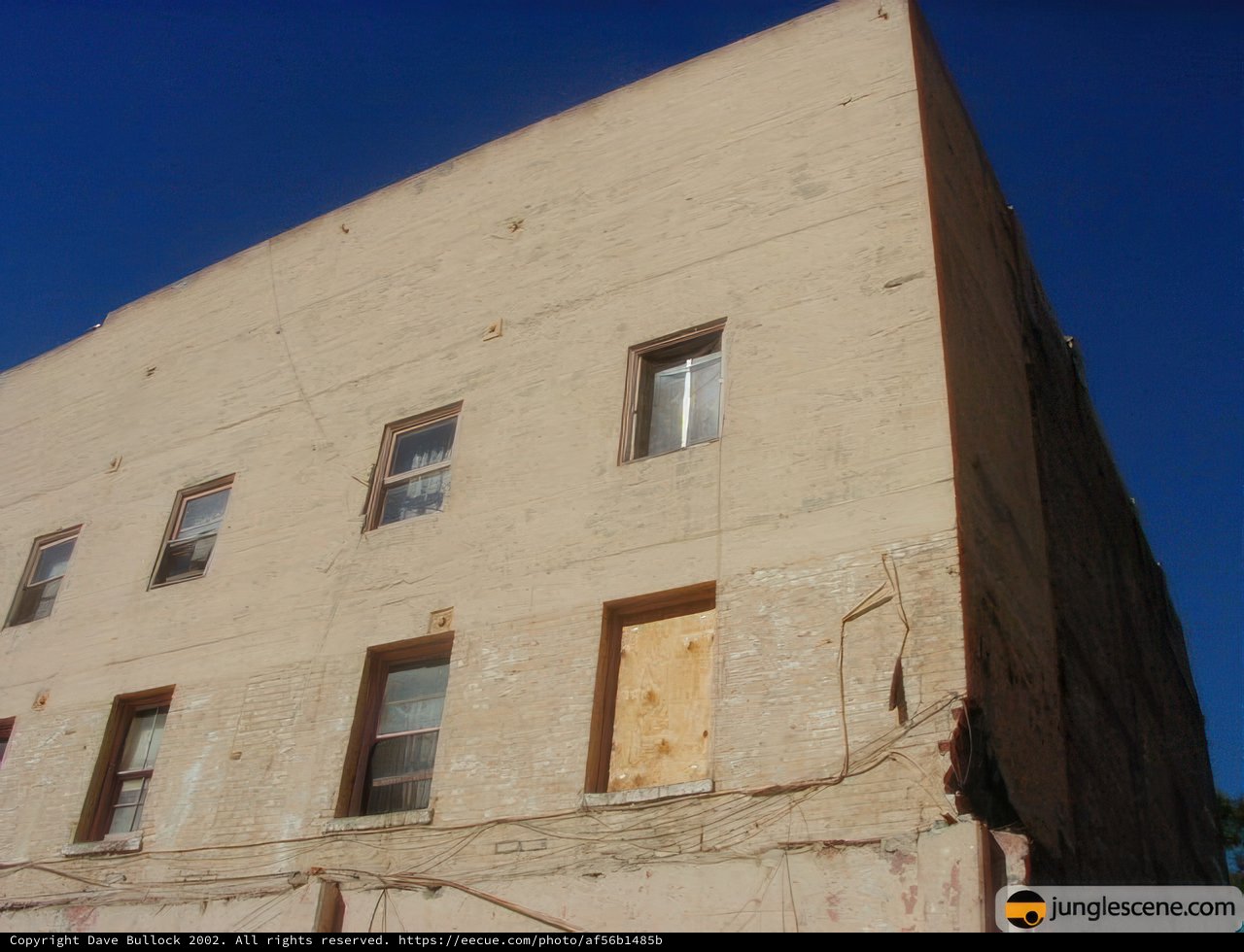 Abandoned Brick Building with Boarded Windows against Blue Sky