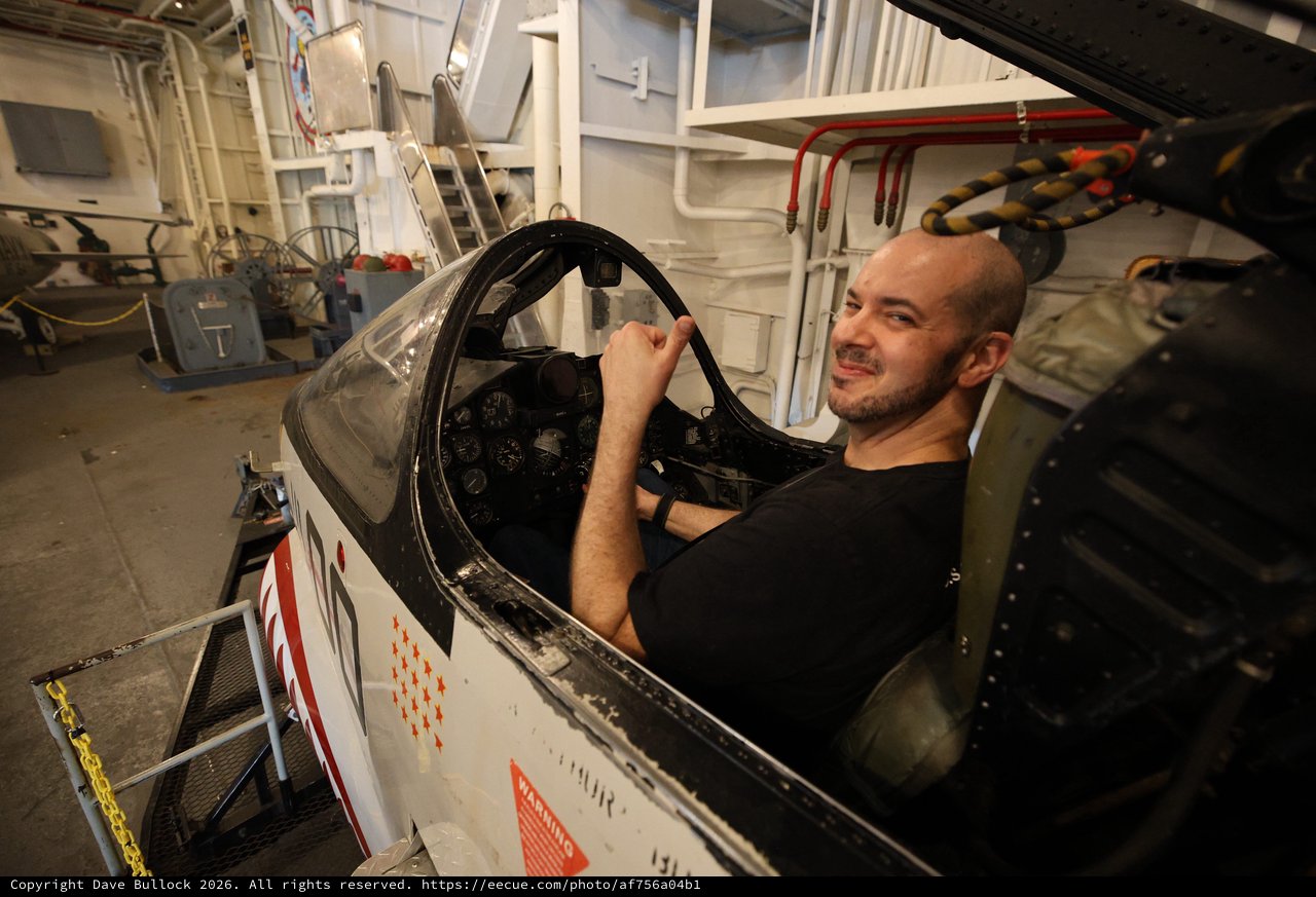 Man Sitting in Vintage Aircraft Cockpit Aboard USS Hornet
