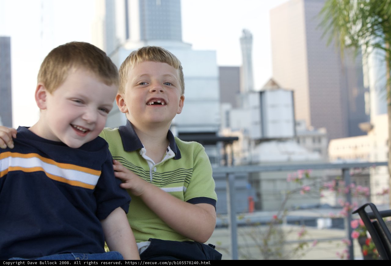 Two boys smiling in front of city skyline