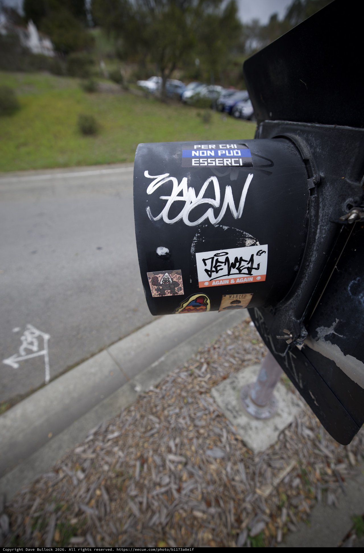 Sticker-Covered Black Mailbox in Suburban Setting