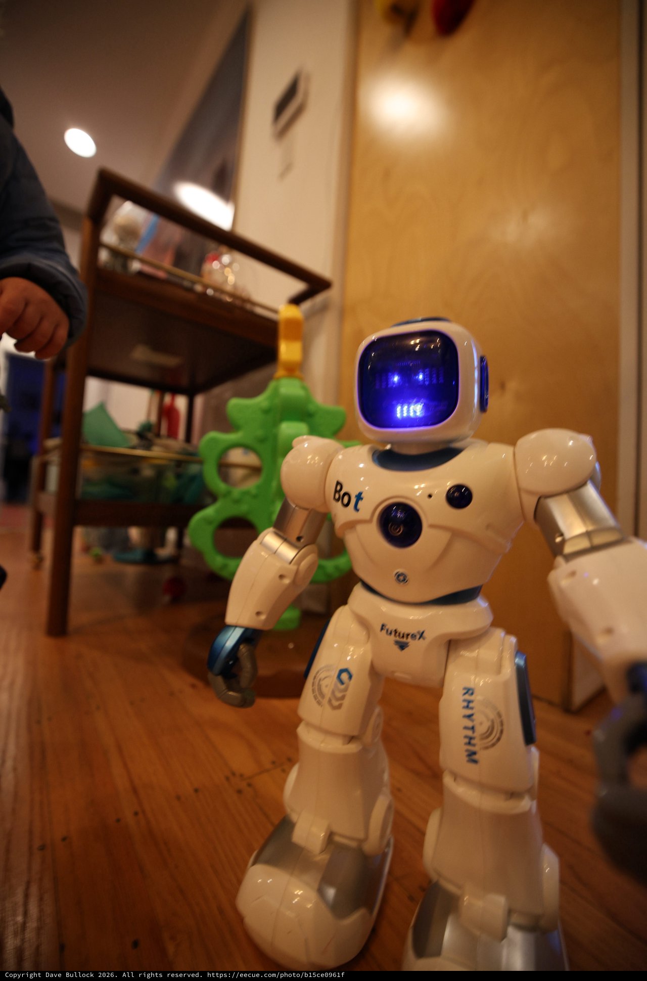 White Robot Toy Standing on Wooden Floor at Home