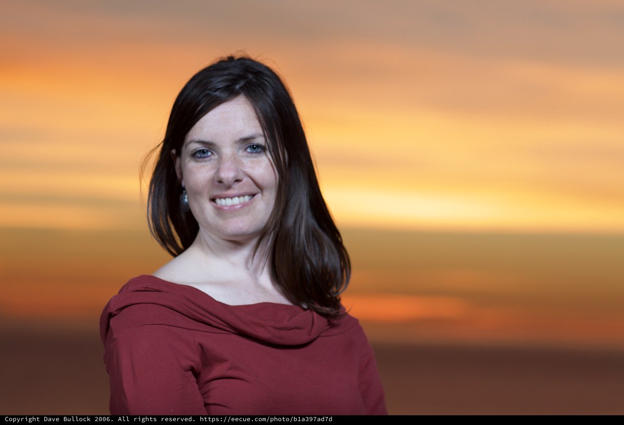 Woman Smiling Radiantly Against Golden Sunset Sky
