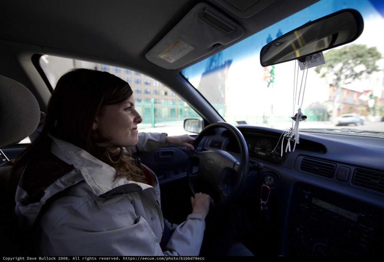 Woman Navigating Urban Streets in Toyota Sedan