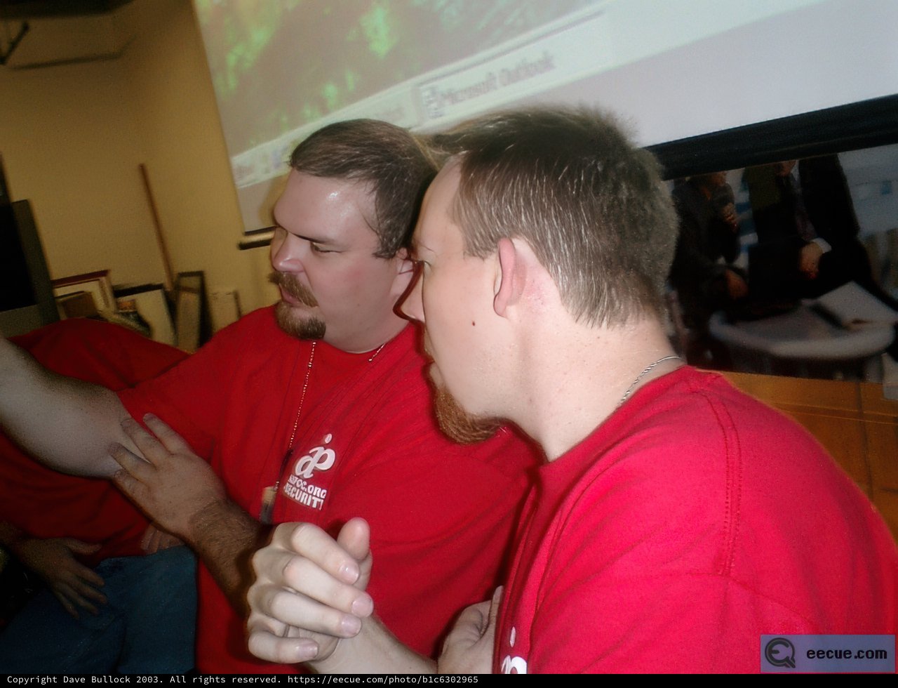 Two Men In Red Shirts Using Computers