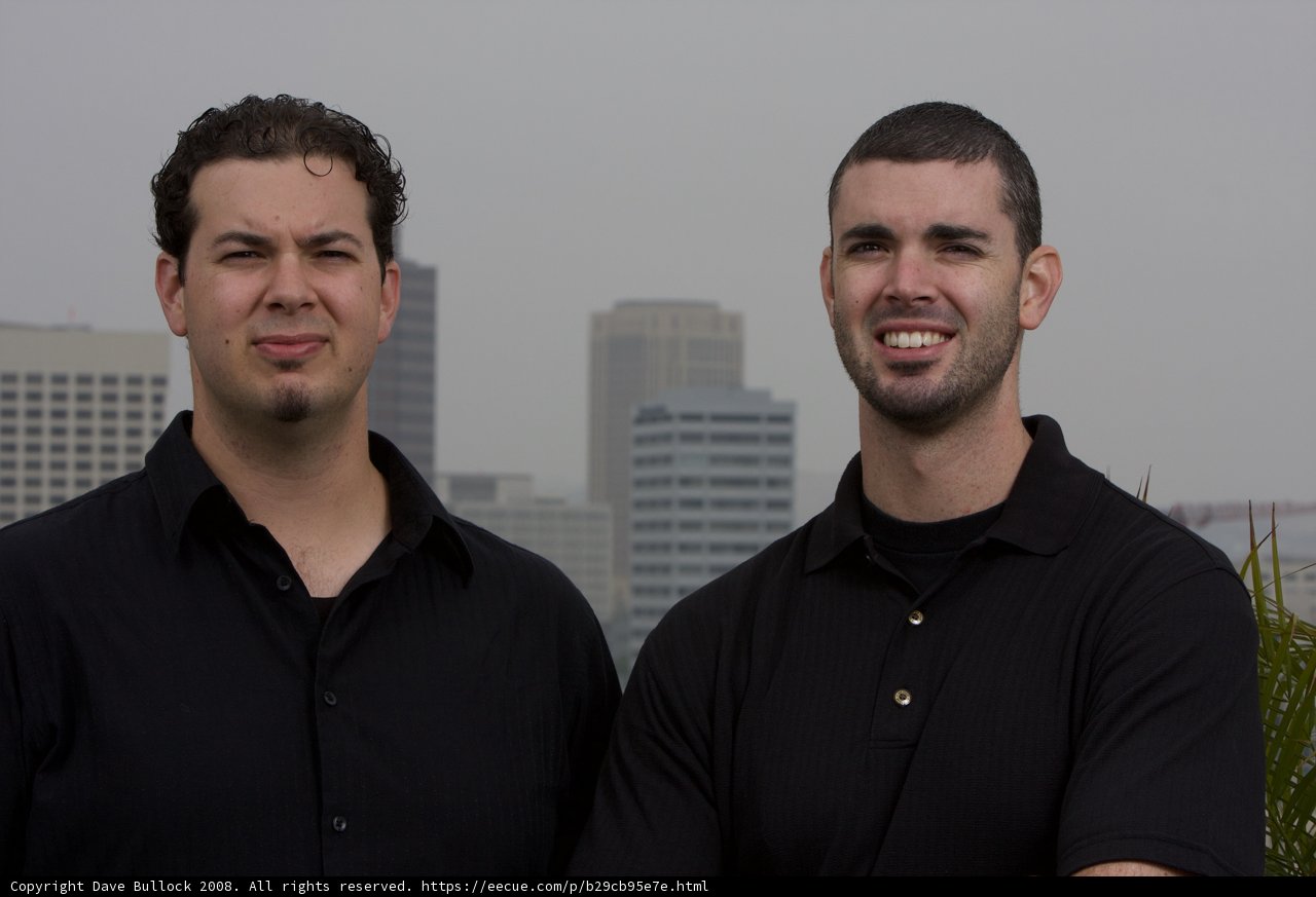 Two Men Smiling in Front of a Skyscraper