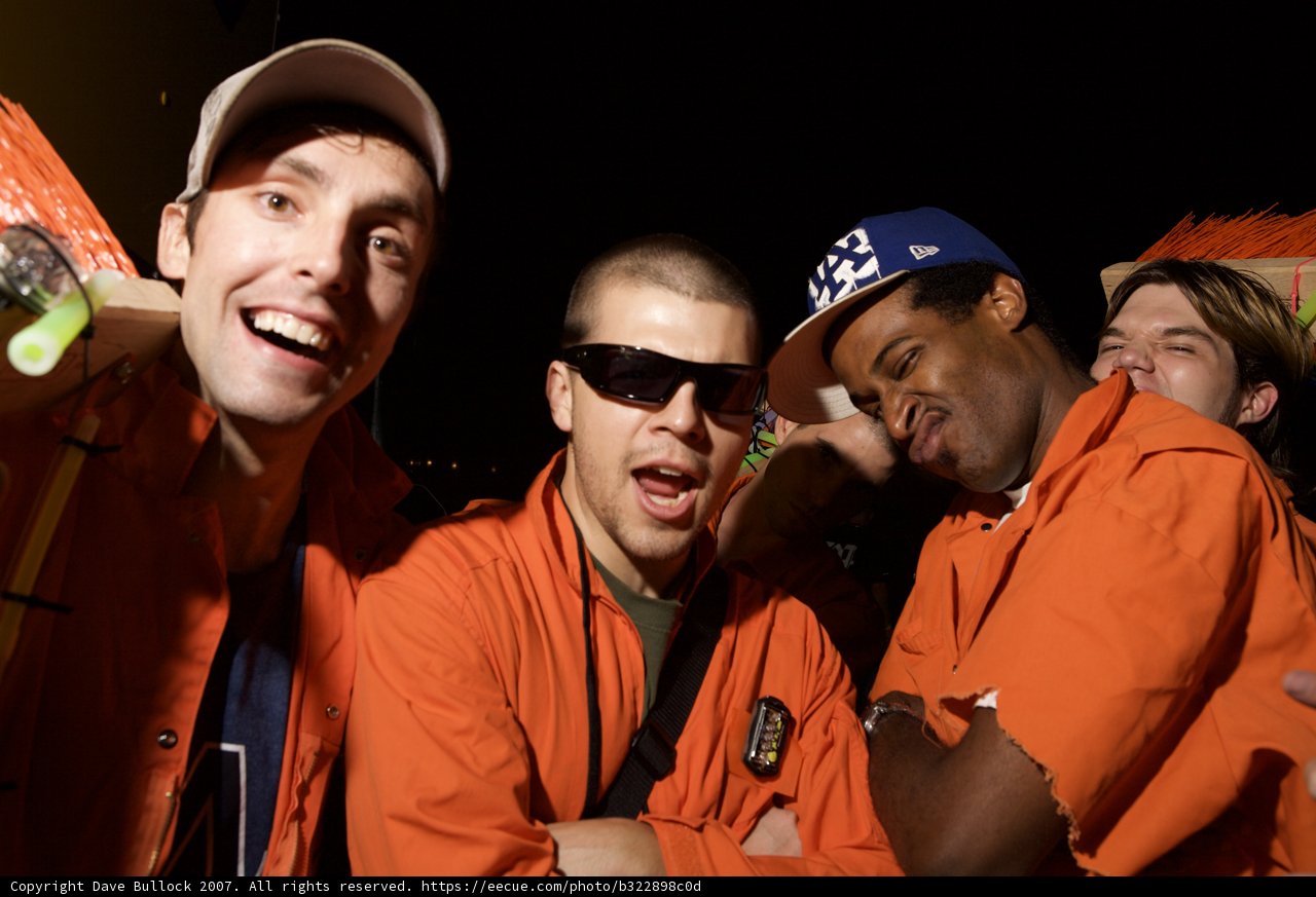 Three men in orange jackets with baseball caps and sunglasses