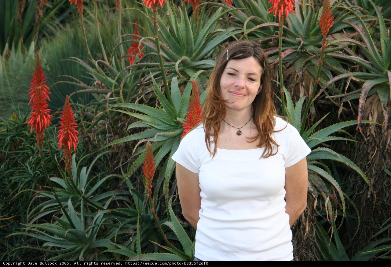 Young Woman Smiling Among Blooming Aloe Plants