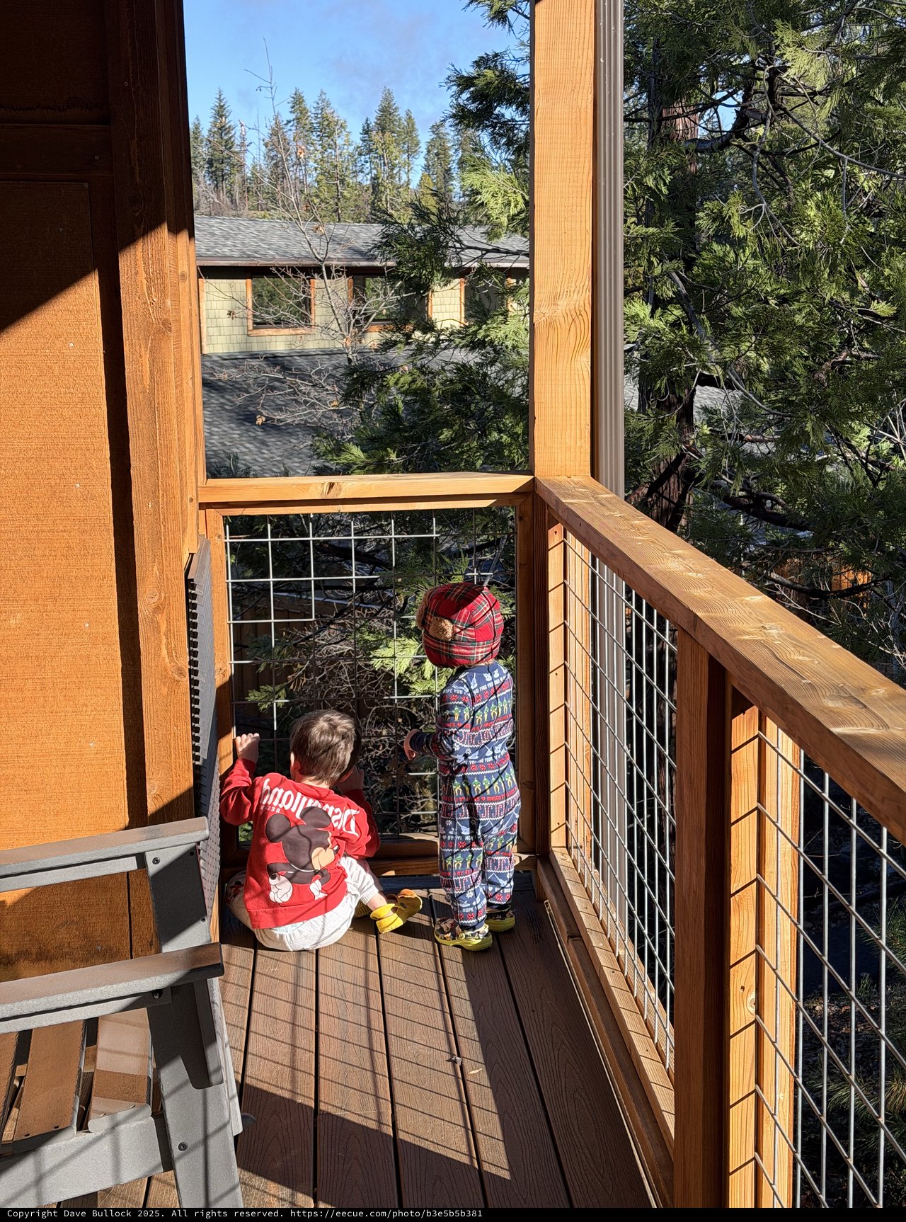 Two Young Children Exploring a Snowy Mountain Cabin Deck