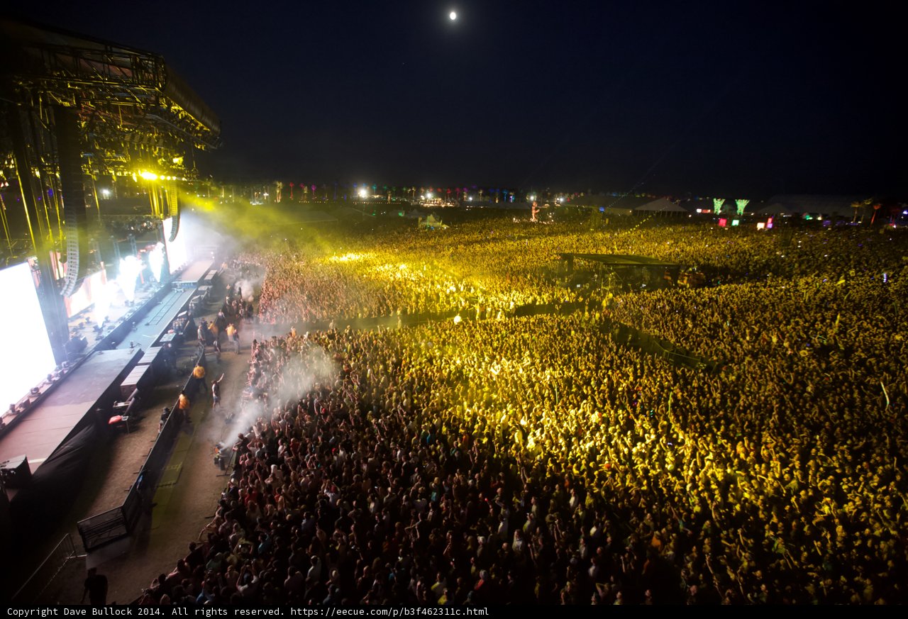 Moonlit Madness Caption: The crowd roars under the night sky at Coachella 2014, as the moon adds a touch of magic to the rock concert atmosphere.