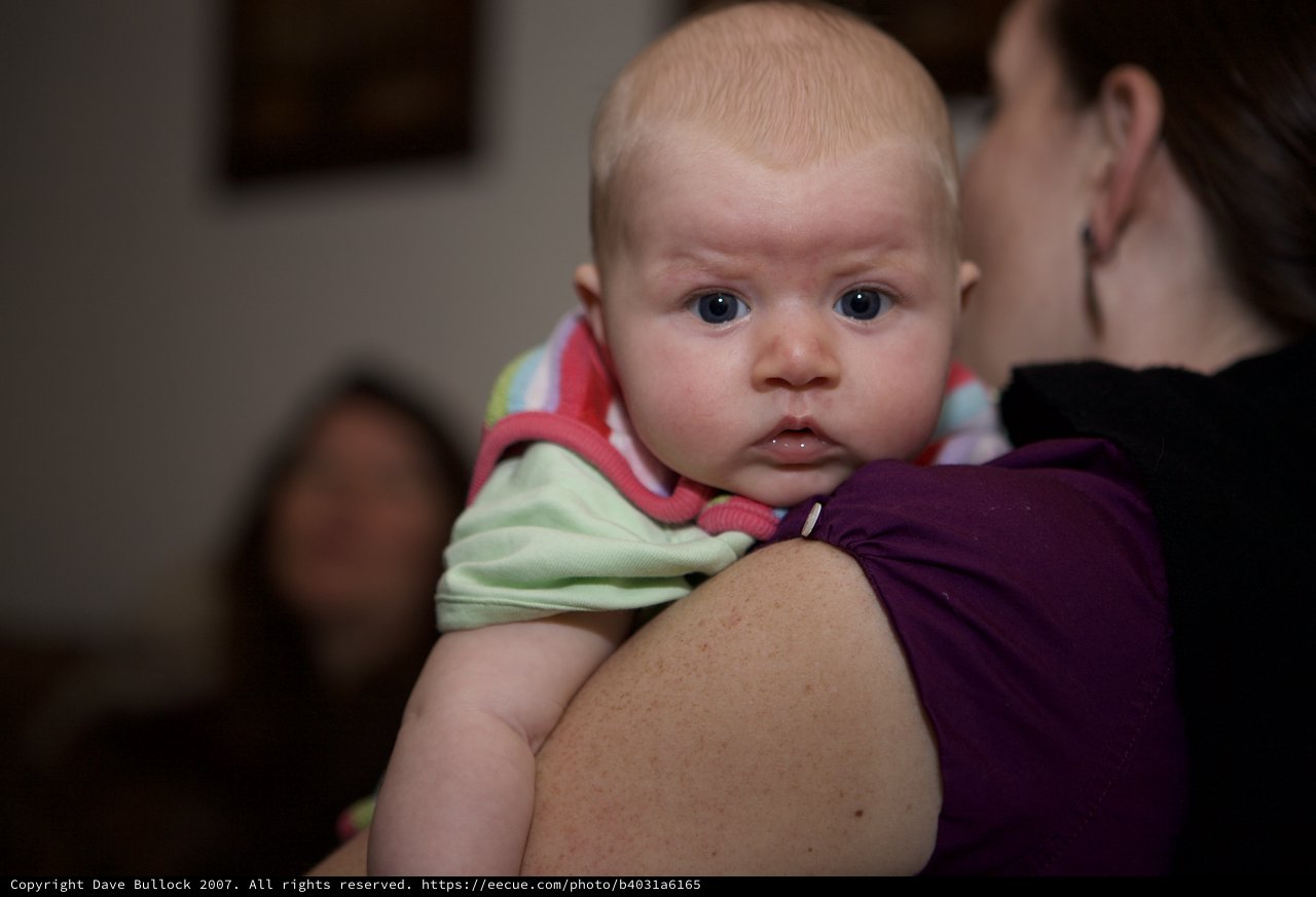 Wide-Eyed Baby Resting on Mother's Shoulder