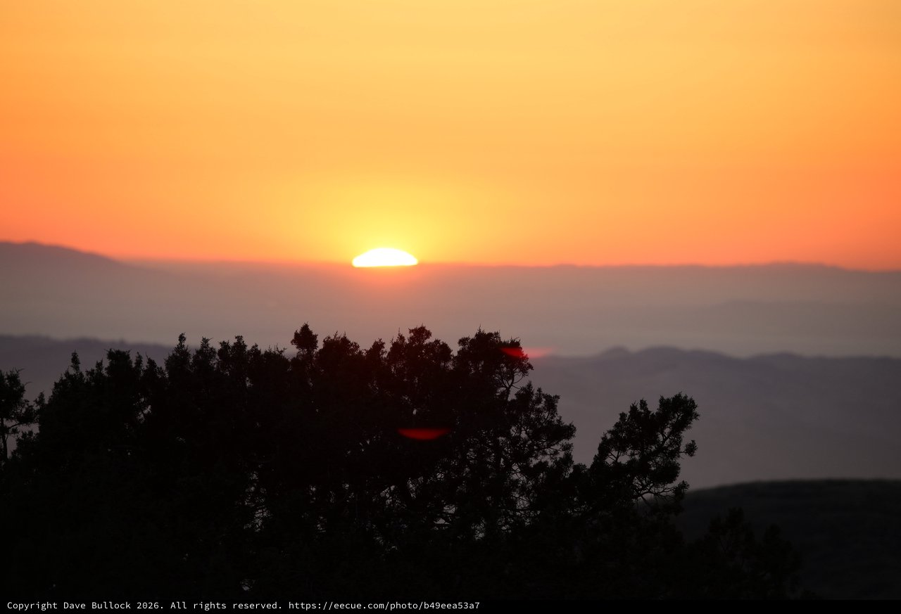 Sun Setting Over Misty Mountain Ridgelines at Dusk