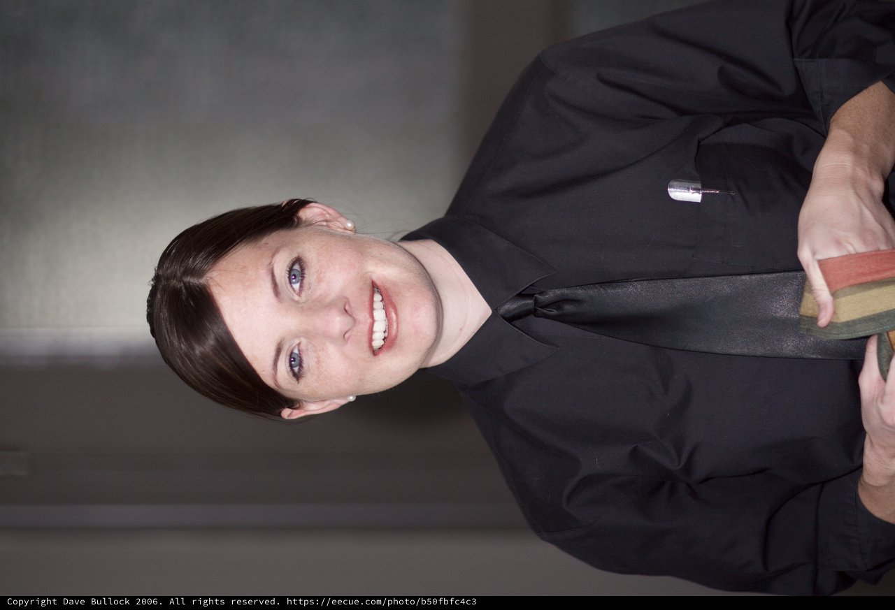 Smiling Server in Black Uniform Holds Menu