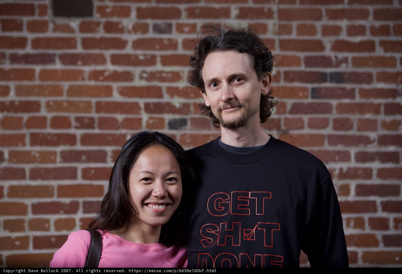 Smiling Couple Poses Against Brick Wall
