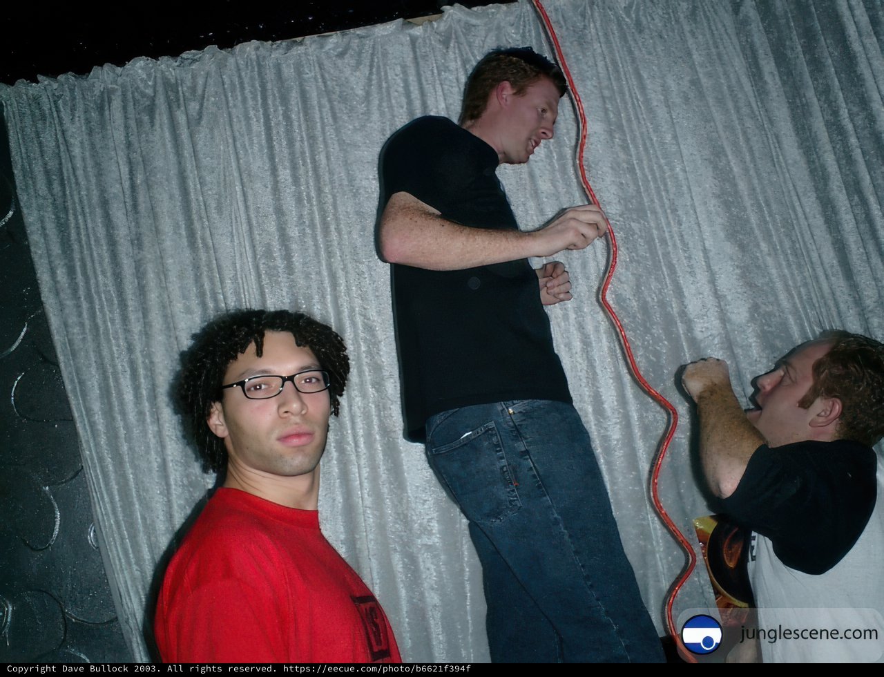 Three Men in Front of Curtain