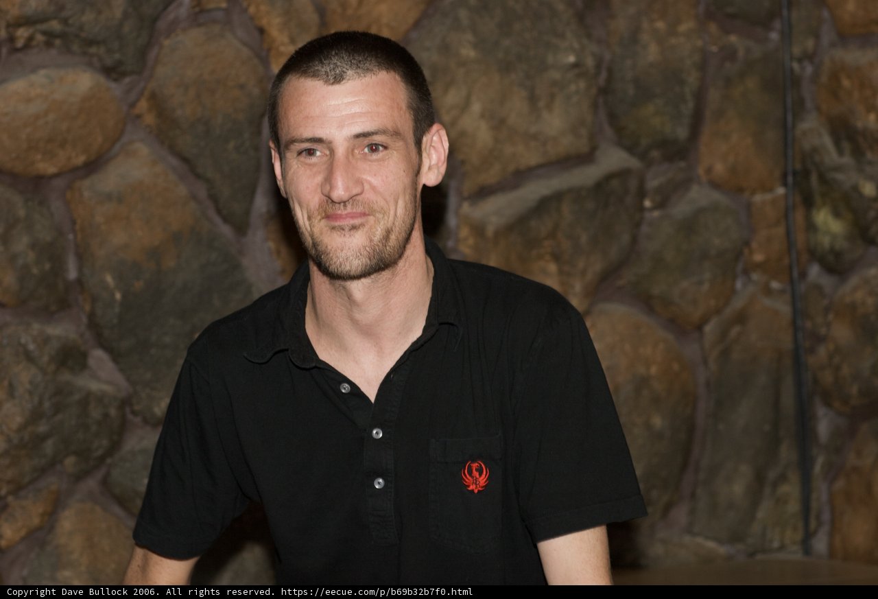 The Happy Man in Black Poses by a Stone Wall