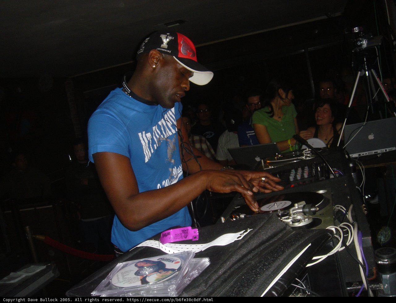 Blue-shirted man working the turntables in a nightclub