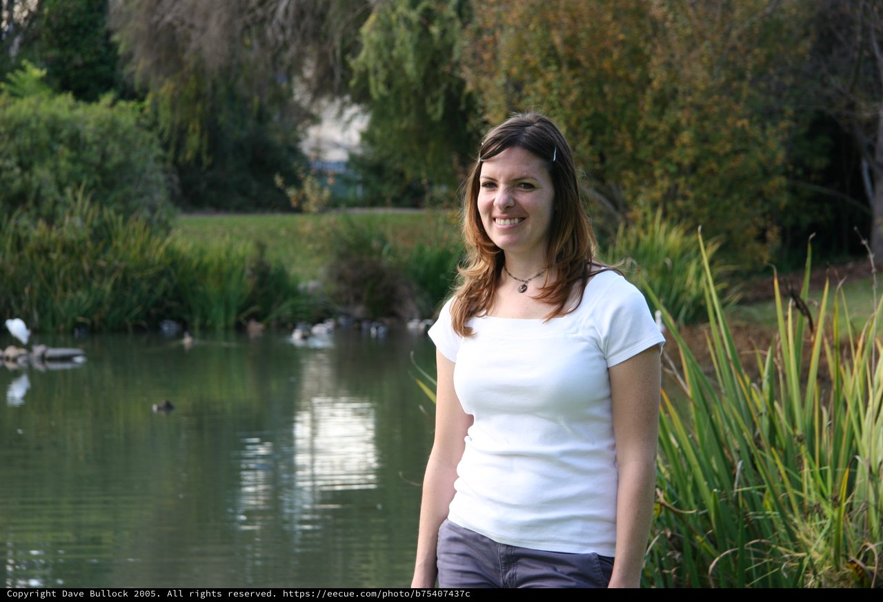 Smiling Woman by a Tranquil Park Pond