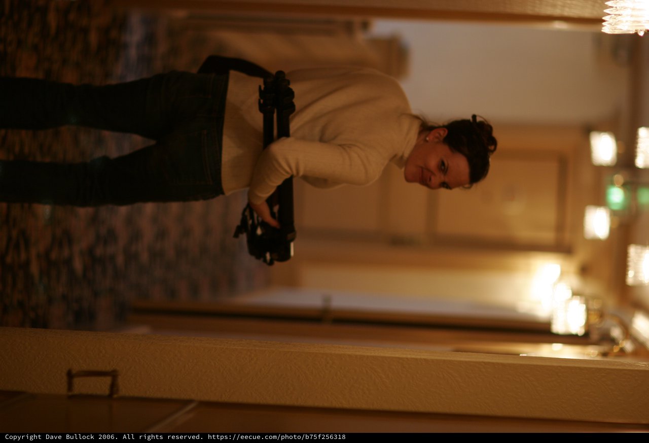 Woman with Tripod Walking Down Hotel Corridor