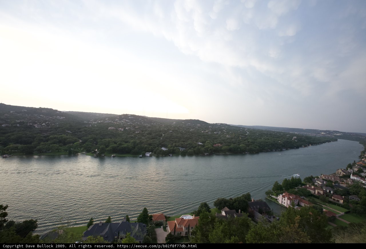 Panoramic View of Lake Austin Caption: A stunning aerial shot of Lake Austin in Texas featuring five buildings, two boats, and a breathtaking view of the surrounding landscape.