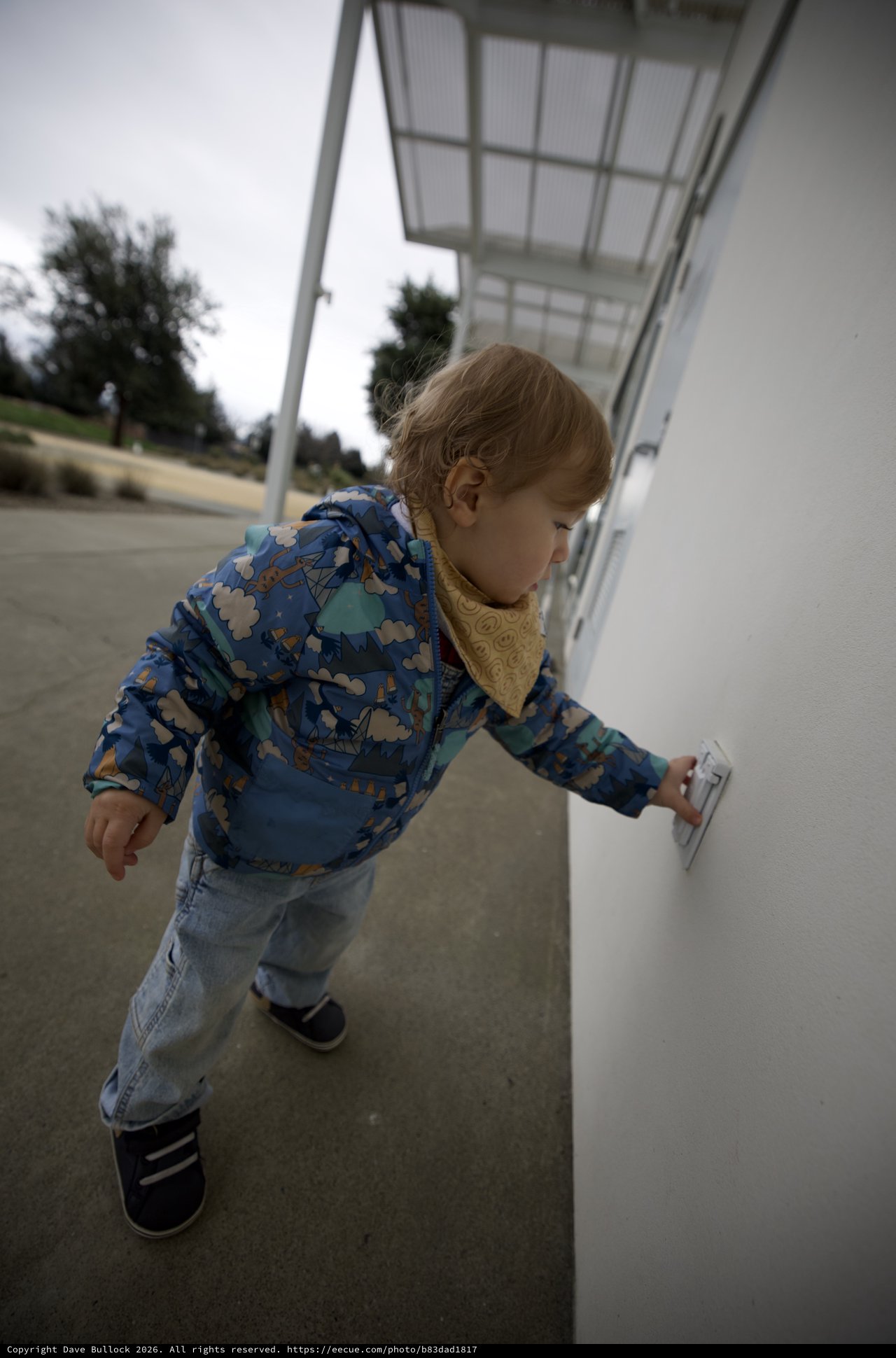 Young Child Exploring White Wall at Outdoor Location