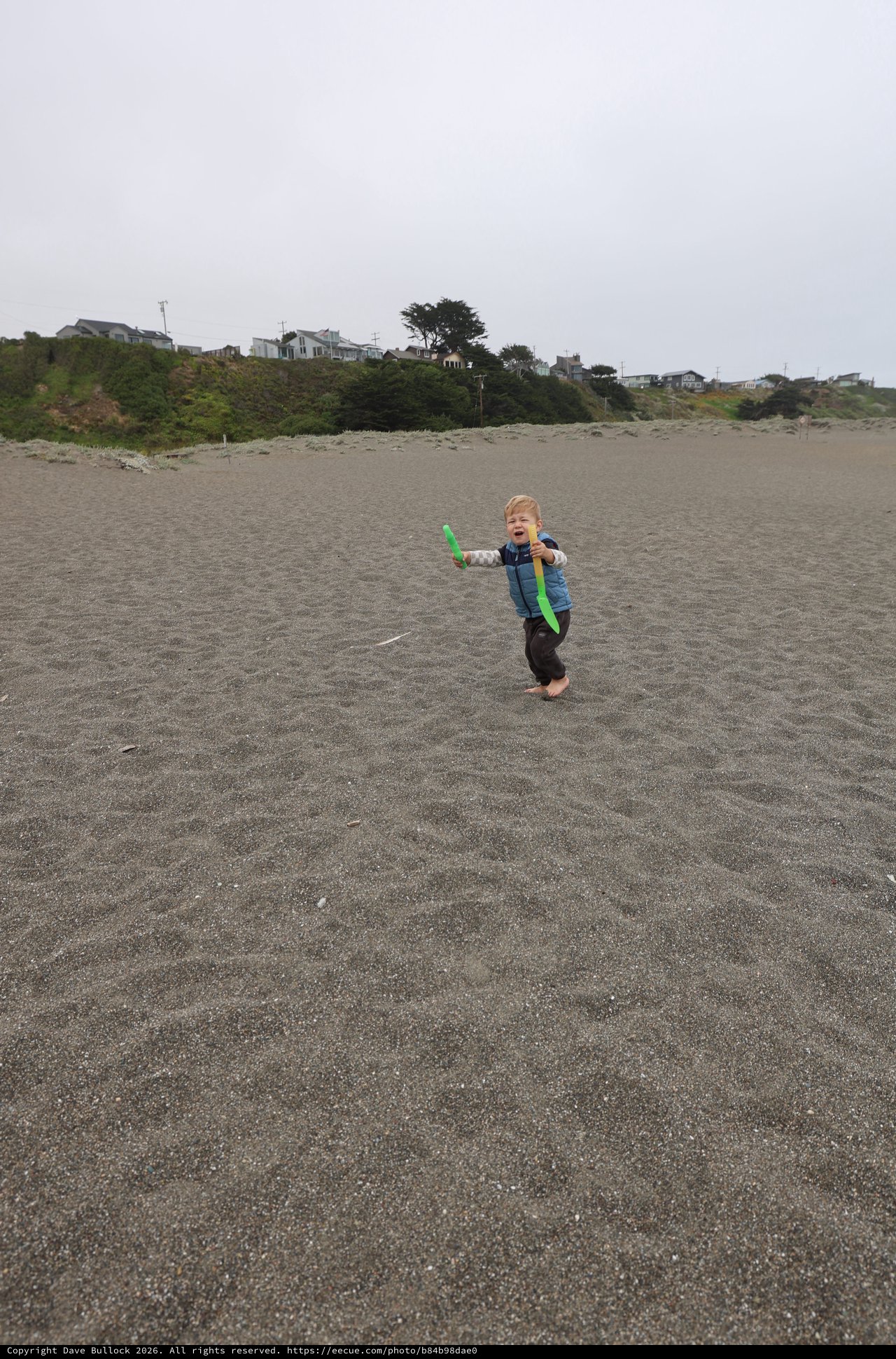 Joyful Toddler Playing with Boomerang on Foggy Beach