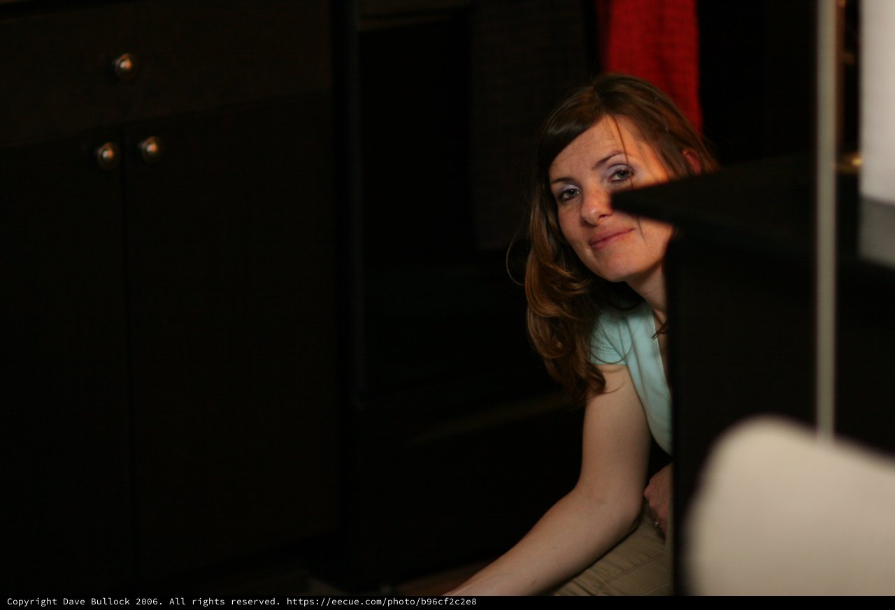 Woman Peering Around Dark Corner with Smile