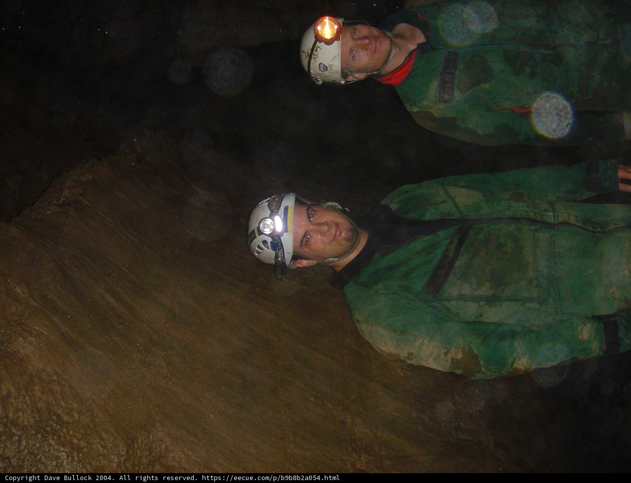 Two Men in Green Jackets Explore Natural Cave