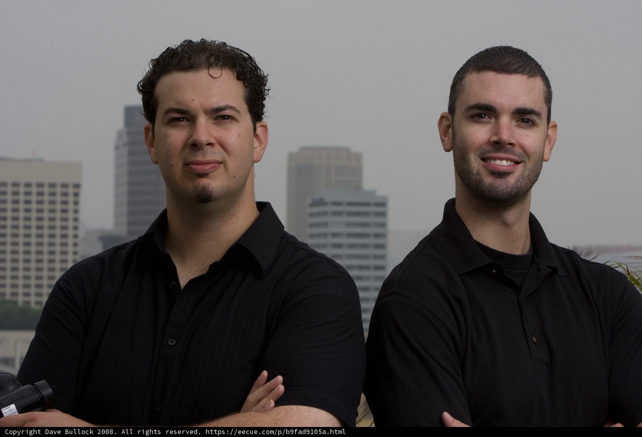 Two Happy Men Pose in Front of a Skyscraper