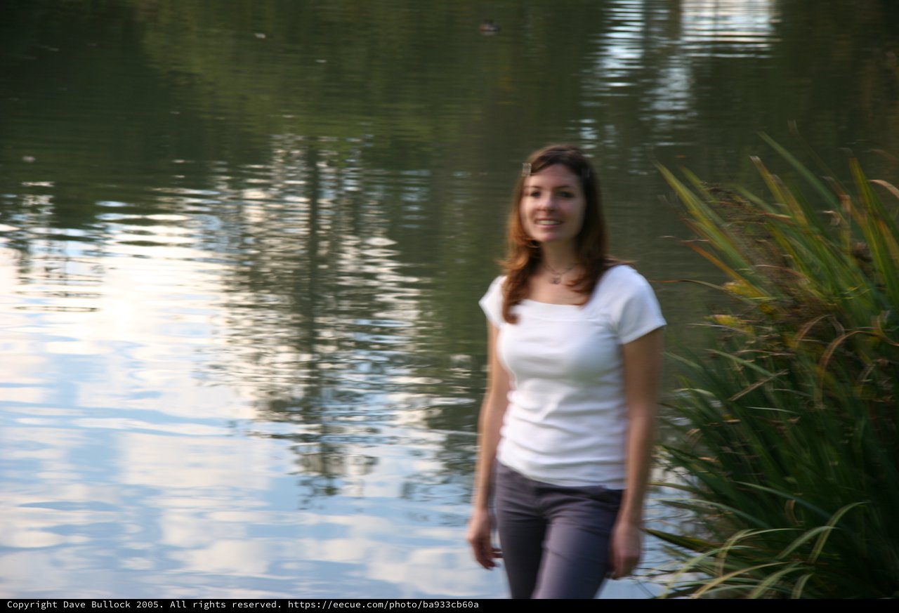 Young Woman Smiling by a Reflective Pond